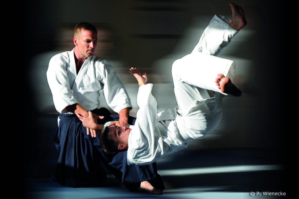 Aikidokas in Action Mann wirft anderen Mann per Aikidogriff zu Boden