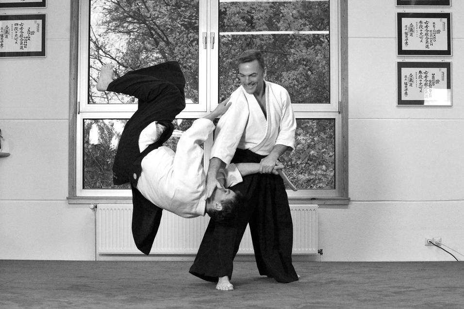 Aikidokas in Action Mann wirft anderen Mann per Aikidogriff zu Boden