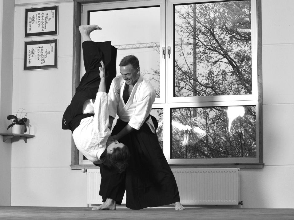 Aikidokas in Action Mann wirft anderen Mann per Aikidogriff zu Boden