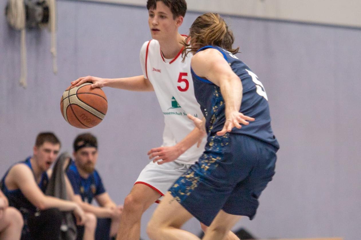 Basketball Punktspiel Reinbeker Basketballer dribbelt heraneilenden Gegenspieler aus.