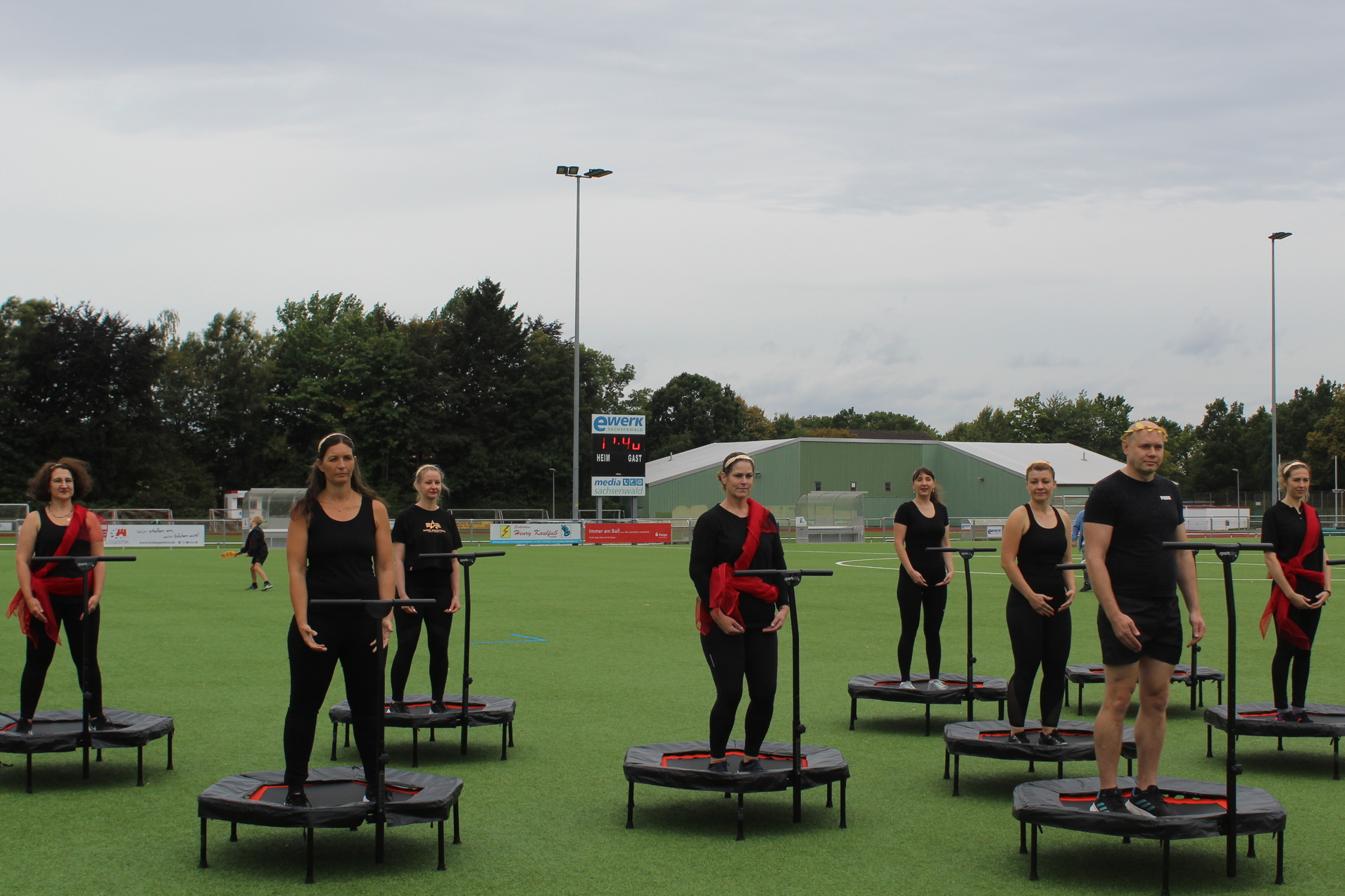 Personen stehen auf kleinen Trampolinen auf dem Kunstrasenplatz