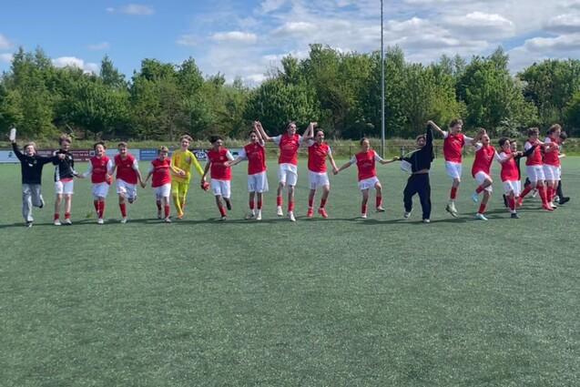 C-Jugend Fu&szlig;baller laufen als Menschenkette jubelnd &uuml;ber den Kunstrasenplatz