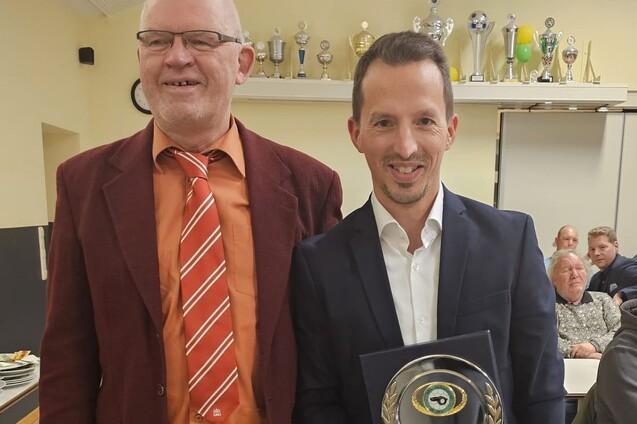 2 M&auml;nner in Anzug. Dennis Krohn pr&auml;sentiert sein Auszeichnung