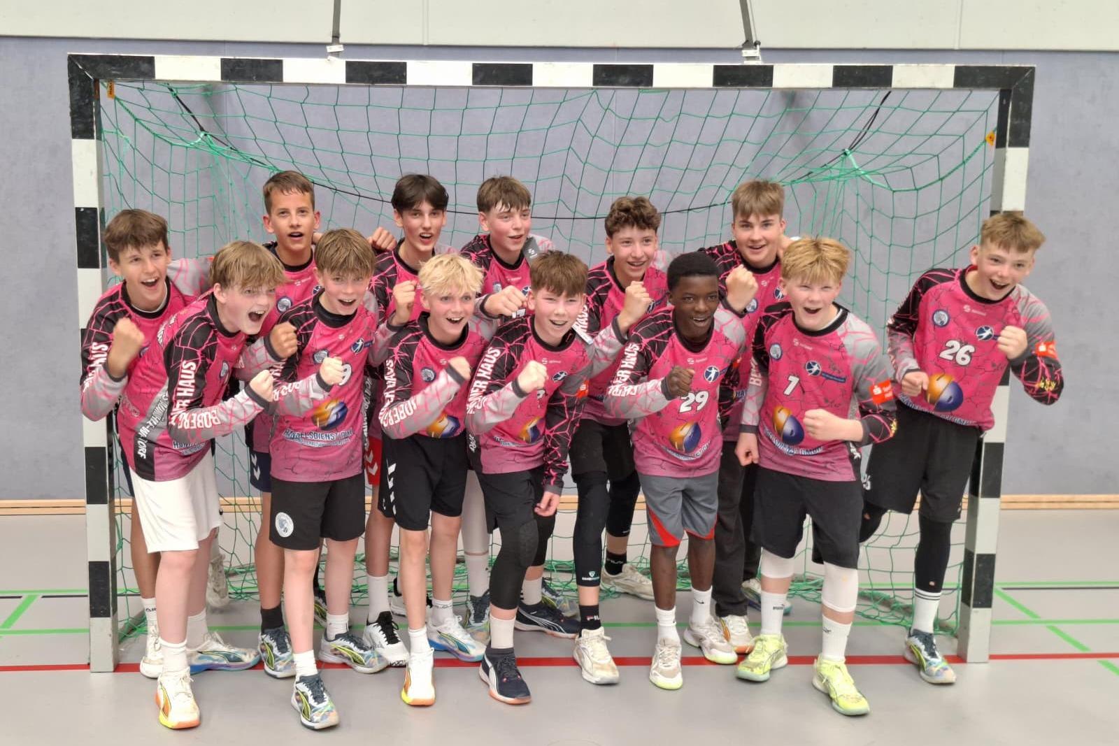 Jugendliche der Handballmannschaft stehen in einem Handballtor und jubeln