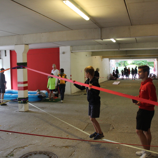 Kind balanciert über eine zwischen den Betonpfeilern der Garage gespannte Slackline.