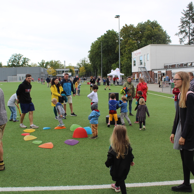 Kinder und Eltern probieren sich am diversen Kleinspielen zu Balance und Geschicklichkeit auf dem Kunstrasen.