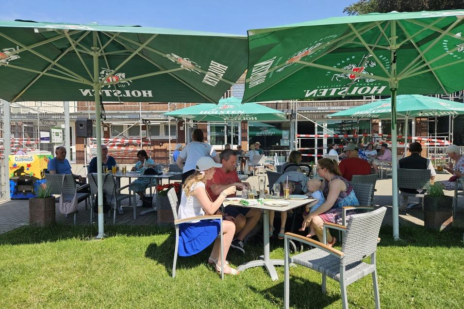 Dankeschönfest Personen sitzen an Tischen draußen unter Sonnenschirmen
