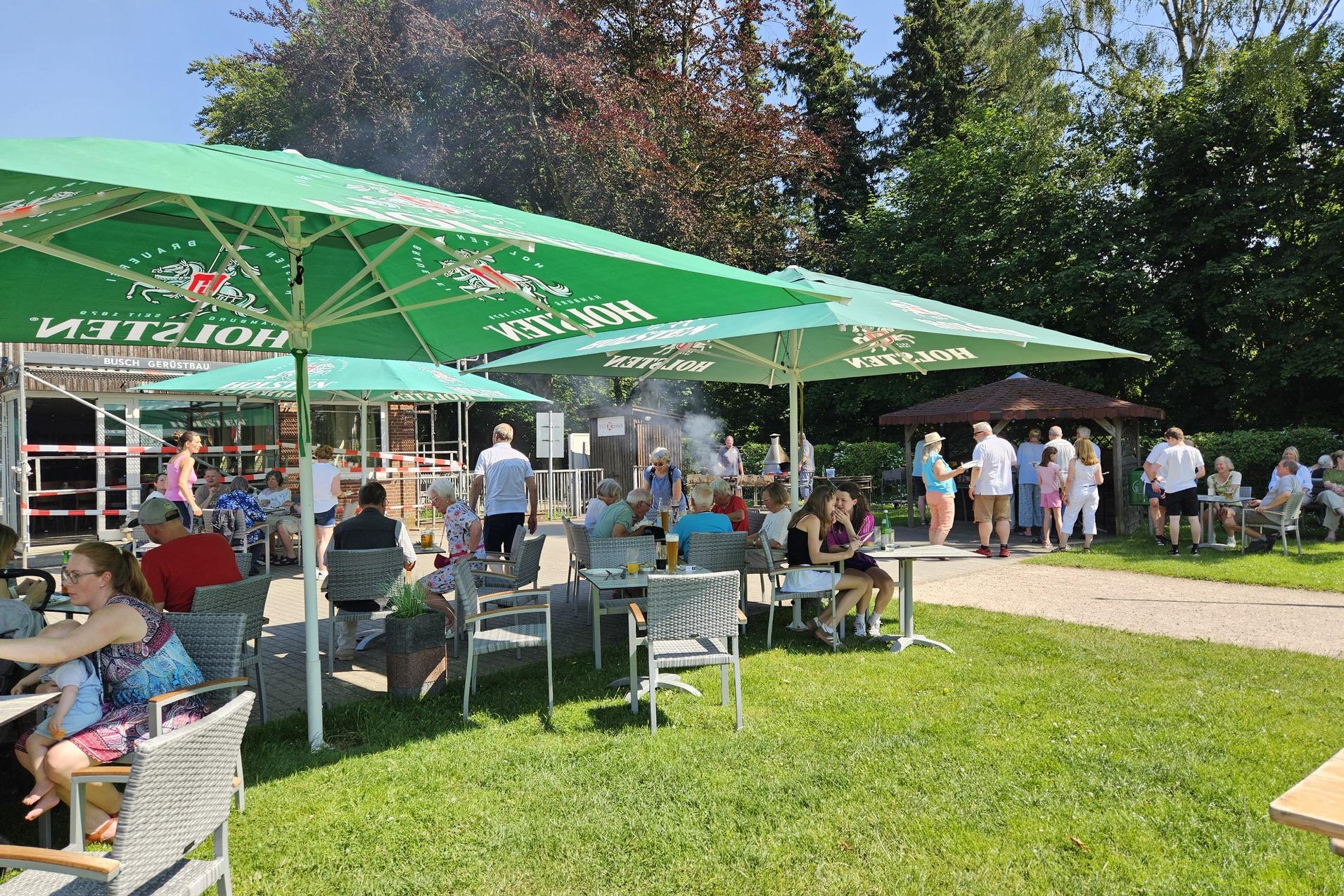 Dankeschönfest Personen sitzen draußen unter Sonnenschirmen und essen