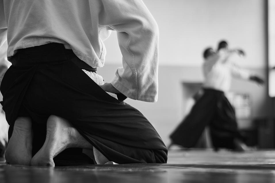 Shutterstock Iaido Kniende Person vorne schaut im Hintergrund kämpfenden Personen zu