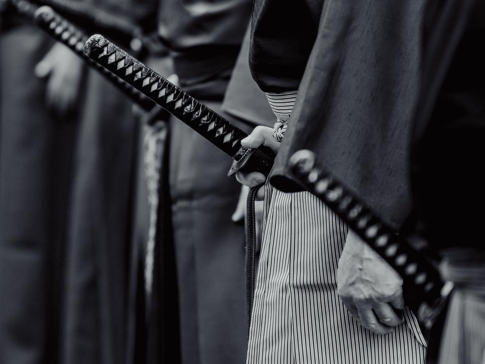 Shutterstock Iaido Ausschnitt von Personengruppe in Reihe mit Schwertern auf Hüfthöhe