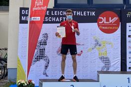 Tim Rummelhagen auf dem Siegerpodest mit Urkunde und Medaille in der Hand.