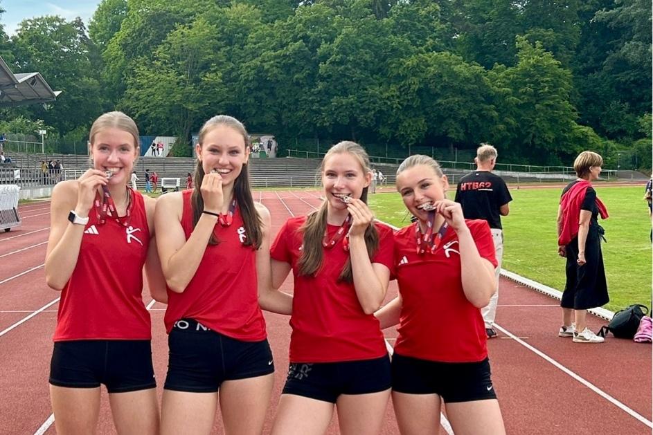 Siegerfoto der Staffelläuferinnen Leichtathletinnen präsentieren ihre Medaille indem sie da reinbeißen