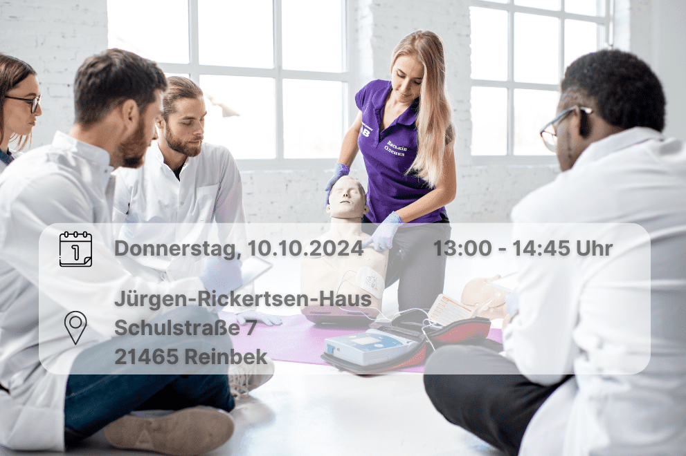 Notfallschulung Oktober 2024 Frau demonstriert Verhalten im Notfall an Plastikpuppe. Weitere Personen sehen ihr dabei zu. Inklusive Orts- und Datumsangabe