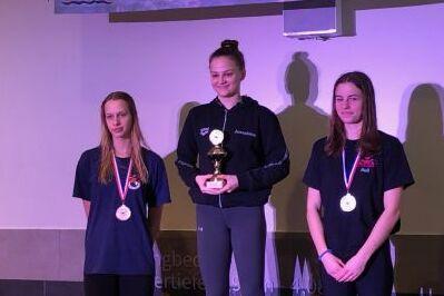 Drei M&auml;dchen auf dem Siegerpodest mit Pokal und Medaillen.