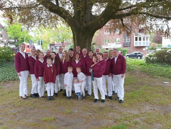 Gruppenbild Spielmannszug Gruppenbild Spielmannszug in rot-weißer Kleidung vor einem Baum.
