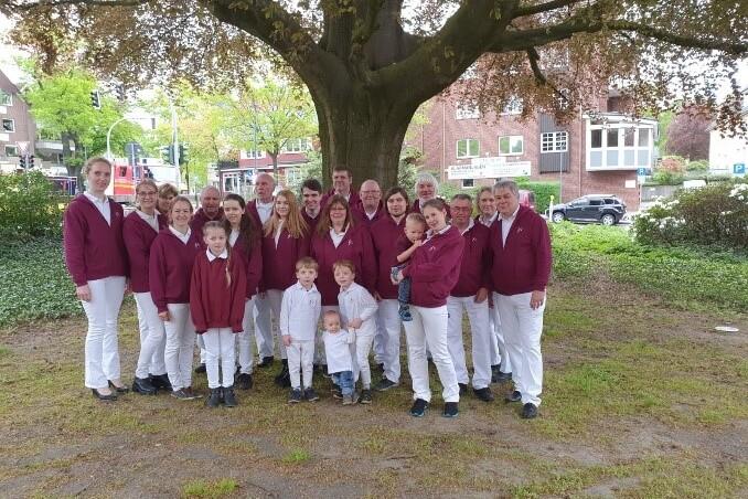 Gruppenbild Spielmannszug Gruppenbild Spielmannszug in rot-weißer Kleidung vor einem Baum.