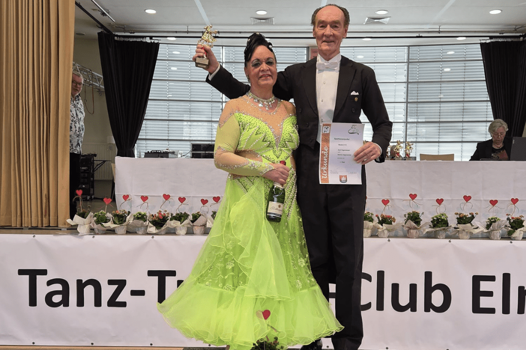 Das Tanzpaar Hagemeister steht auf einem Podest. Axel Hagemeister h&auml;lt eine Urkunde in der Hand