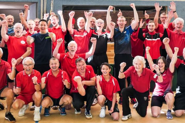 Gruppenbild von TischtennisspielerInnen in der Sporthalle. Die Arme sind in die Höhe gestreckt.