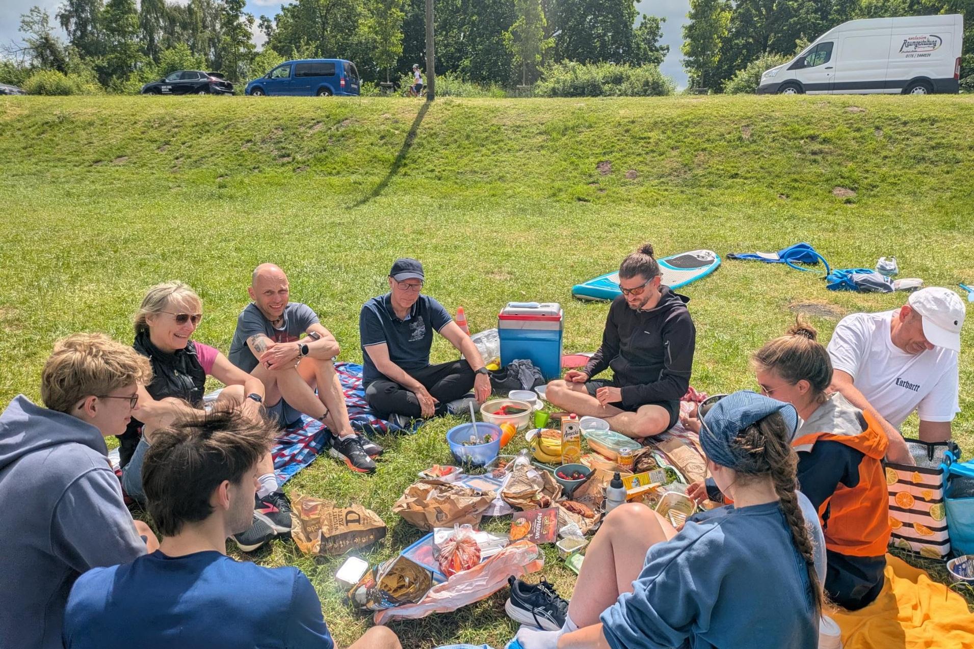 Probetriathlon 2026 Triathleten sitzen beim Picknick und Erfahrungsaustausch auf der Wiese.