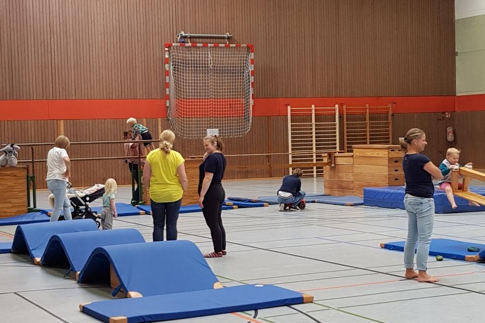 Turnlandschaft, in der sowohl Erwachsene zuschauen als Kinder turnen
