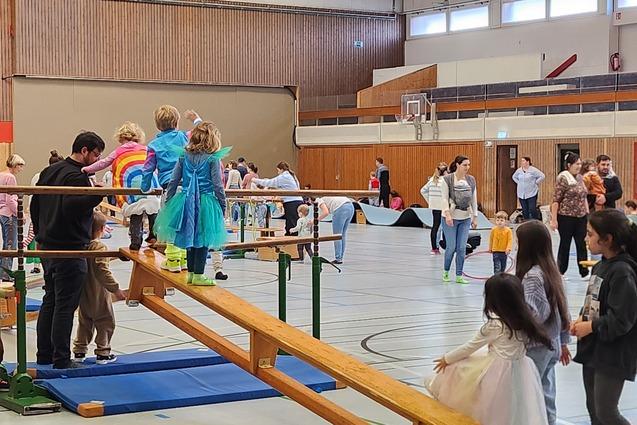Turnlandschaft, in der kostümierte Kinder und ihre Eltern turnen und spielen