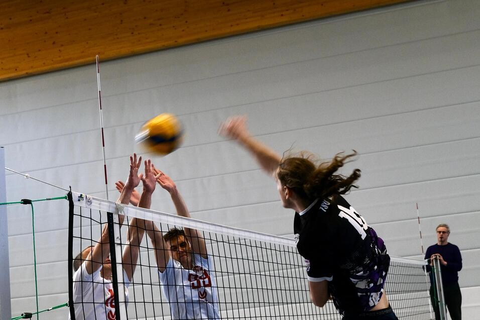 Spielszene bei der zwei Verteidiger im Sprung den gerade geschlagenen Angriff am Netz blocken wollen