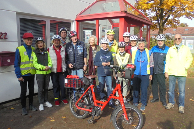 14 RadlerInnen haben sich inklusive eines roten Fahrrades vor dem Eingang zur TSV Geschäftsstelle für ein Gruppenfoto aufgestellt.