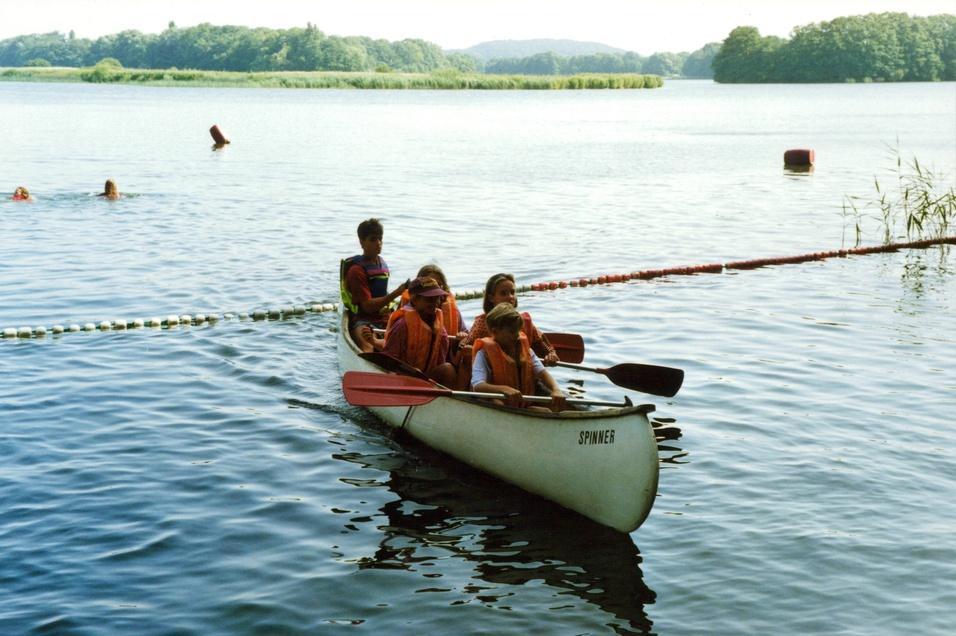 Teilnehmer der Jugendreise sitzen im Kanu, das sich im Wasser befindet