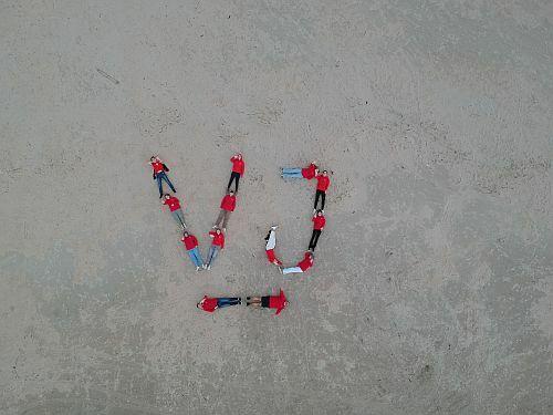 Drohnenbild der Mitglieder der Vereinsjugend, die den Schriftzug VJ mit ihren Körpern auf dem Strand darstellen.