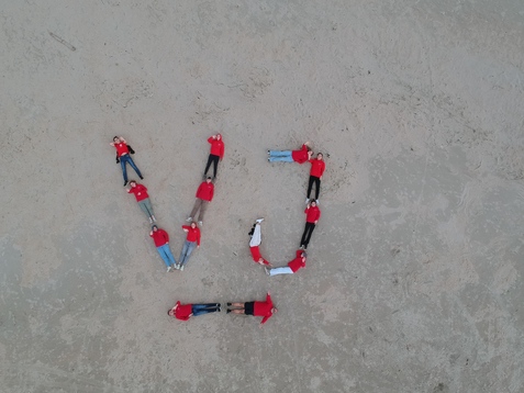 Drohnenbild der Mitglieder der Vereinsjugend, die den Schriftzug VJ mit ihren Körpern auf dem Strand darstellen.