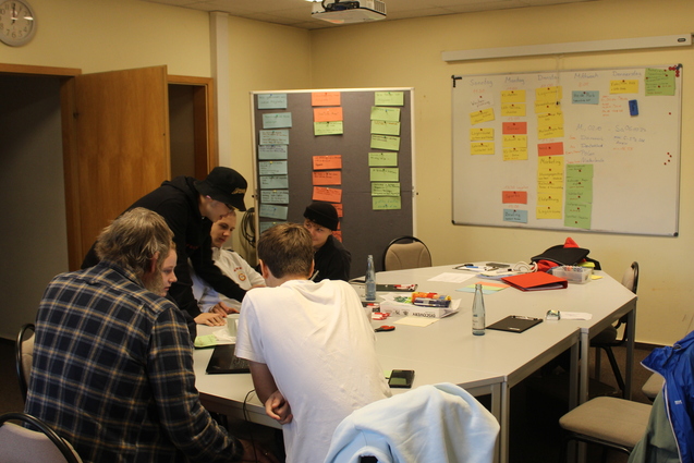 Mitglieder der Vereinsjugend sitzen im Sitzungsraum um einen Tisch. Im Hintergrund stehen Stellw&auml;nde und ein Whiteboard mit vielen Notizen.