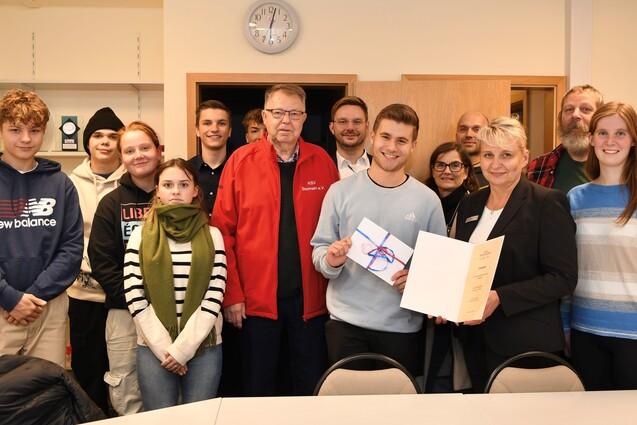 Gruppenfoto mit Luis Kurpjuhn in der Mitte bei der Verleihung der Auszeichnung zum Vereinsheld des Monats. Neben ihm stehen Mitglieder der Vereinsjugend, des Kreissportverbandes Stormarn und der Sparkasse Holstein.