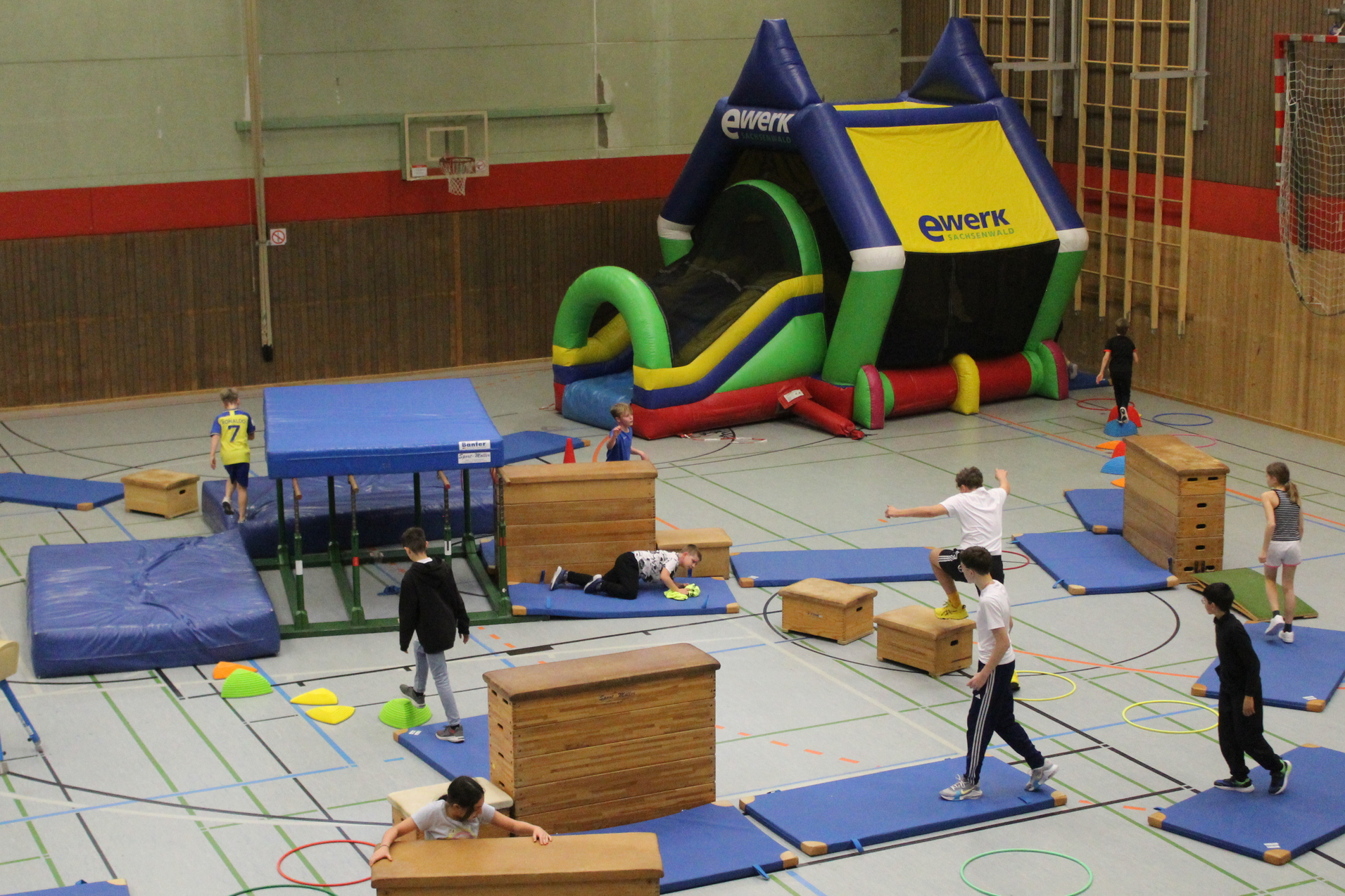 Kinder spielen Ticken in einem Parcours mit vielen Turngeräten und einer Hüpfburg.