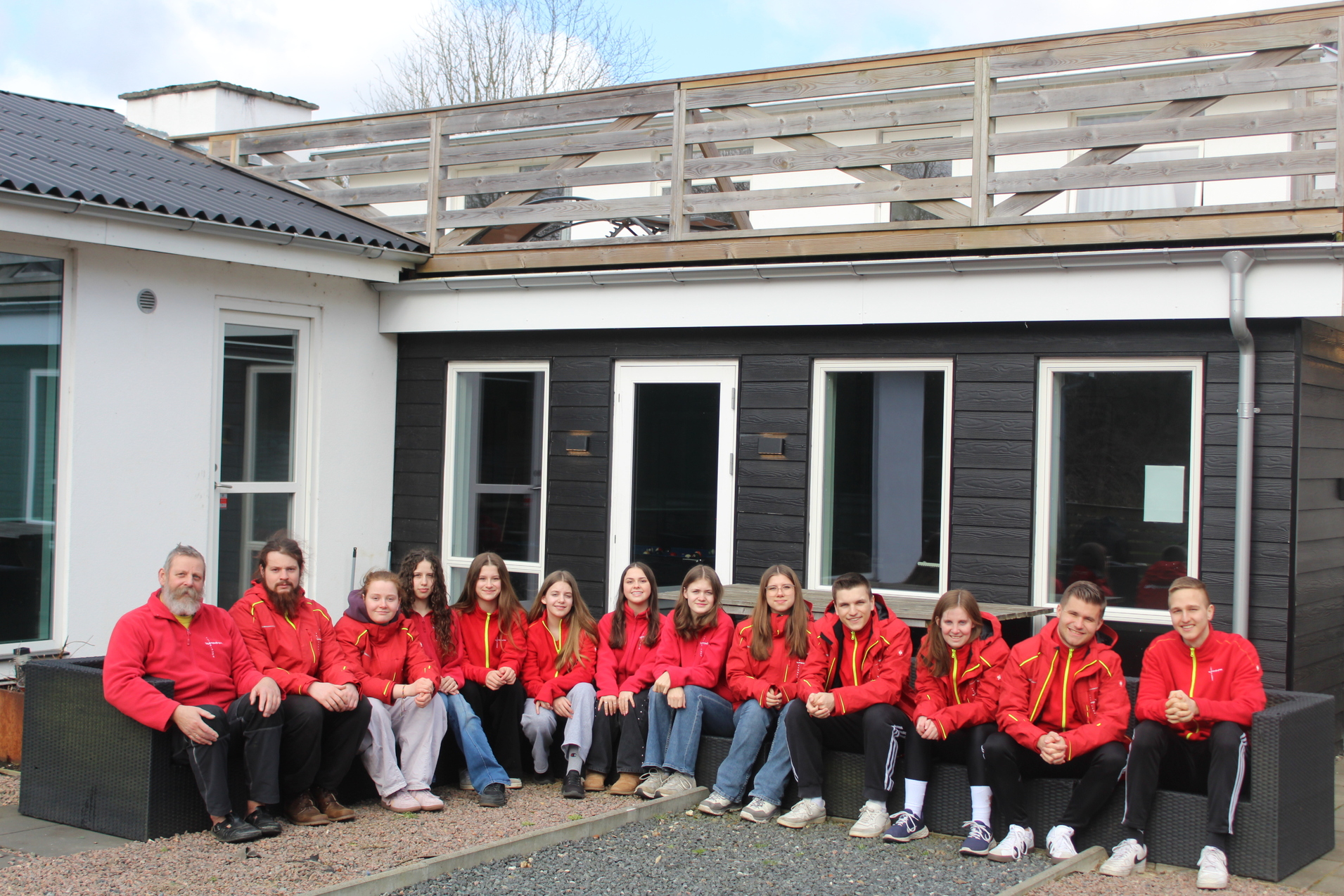 Teilnehmer des Fr&uuml;hlingsseminars sitzen in einer Sitzecke vor dem Haus